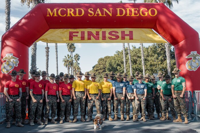 U.S. Marine Corps drill instructors with Recruit Training Regiment, pose for a photo with Lance Cpl. Bruno, the  Marine Corps Recruit Depot San Diego and Western Recruiting Region mascot, at the finish line during the 2024 Marine Corps Recruit Depot San Diego Boot Camp Challenge at MCRD San Diego, California, Oct. 19, 2024. For the past 23 years, MCRD San Diego has hosted the Boot Camp Challenge, a three-mile obstacle course race guided by 60 drill instructors that highlights the physical and mental demands of bootcamp. The event fosters comradery and community engagement through interaction with MCRD personnel. (U.S. Marine Corps photo by Cpl. Sarah M. Grawcock)