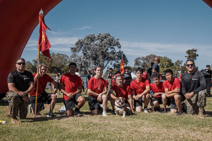 U.S. Marine Corps Lance Cpl. Bruno, the Marine Corps Recruit Depot San Diego and Western Recruiting Region mascot, poses for a photo with Marines and prospective applicants from the San Diego area before the 2024 Marine Corps Recruit Depot San Diego Boot Camp Challenge at MCRD San Diego, California, Oct. 19, 2024. For the past 23 years, MCRD San Diego has hosted the Boot Camp Challenge, a three-mile obstacle course race guided by 60 drill instructors that highlights the physical and mental demands of bootcamp. The event fosters comradery and community engagement through interaction with MCRD personnel. (U.S. Marine Corps photo by Cpl. Sarah M. Grawcock)
