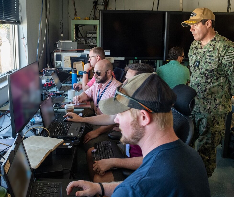 NavalX Gulf Coast Tech Bridge exercise participants gather and relay information from their respective vehicles on the Florida Gulf Coast Test Ranges, Aug. 14. The NavalX Gulf Coast Tech Bridge partner commands: Naval Surface Warfare Center, Panama City Division, Naval Research Lab (NRL) Stennis, Naval Meteorology and Oceanography Command, and the Naval Oceanographic Office collaborated to demonstrate the acceleration of technology development. Capt. Daniel Mirelez, Office of Naval Research Science and Technology reservist, observes (front to back) Dylan Duncan, NSWC PCD, Matthew Vicari, NRL, Nick Moran, NRL, and Chris Coward, NSWC PCD. (U.S. Navy photo by Anthony Powers)