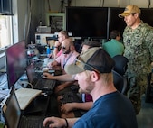 NavalX Gulf Coast Tech Bridge exercise participants gather and relay information from their respective vehicles on the Florida Gulf Coast Test Ranges, Aug. 14. The NavalX Gulf Coast Tech Bridge partner commands: Naval Surface Warfare Center, Panama City Division, Naval Research Lab (NRL) Stennis, Naval Meteorology and Oceanography Command, and the Naval Oceanographic Office collaborated to demonstrate the acceleration of technology development. Capt. Daniel Mirelez, Office of Naval Research Science and Technology reservist, observes (front to back) Dylan Duncan, NSWC PCD, Matthew Vicari, NRL, Nick Moran, NRL, and Chris Coward, NSWC PCD. (U.S. Navy photo by Anthony Powers)