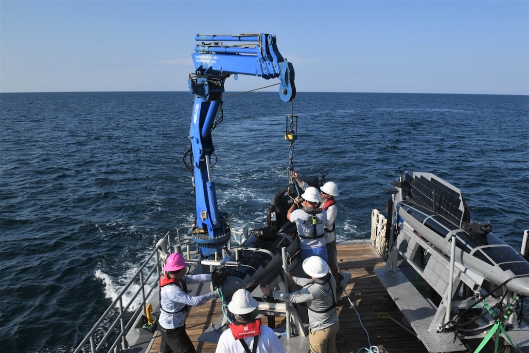 NavalX Gulf Coast Tech Bridge exercise participants work together to launch a Triton using a crane on the Florida Gulf Coast Test Ranges, Aug. 15. (Counterclockwise from left) Alain Aznaran, Paul Moser, Derek Hayes, Brent Stephens and James Dolan. This exercise illustrated a process for rapidly moving from focusing on warfighters' needs, to sourcing technologies, and executing successful experiments to demonstrate emerging capabilities. (U.S. Navy photo by Eddie Green)