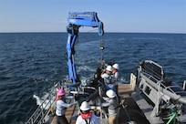 NavalX Gulf Coast Tech Bridge exercise participants work together to launch a Triton using a crane on the Florida Gulf Coast Test Ranges, Aug. 15. (Counterclockwise from left) Alain Aznaran, Paul Moser, Derek Hayes, Brent Stephens and James Dolan. This exercise illustrated a process for rapidly moving from focusing on warfighters' needs, to sourcing technologies, and executing successful experiments to demonstrate emerging capabilities. (U.S. Navy photo by Eddie Green)