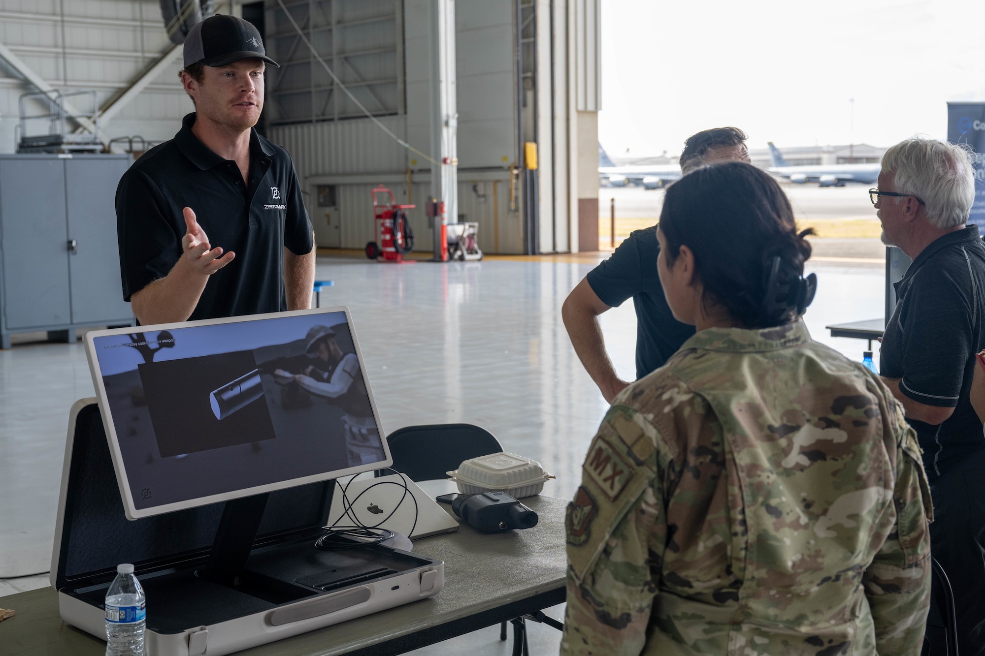 A man stands behind a screen and speaks to a U.S. Airman.
