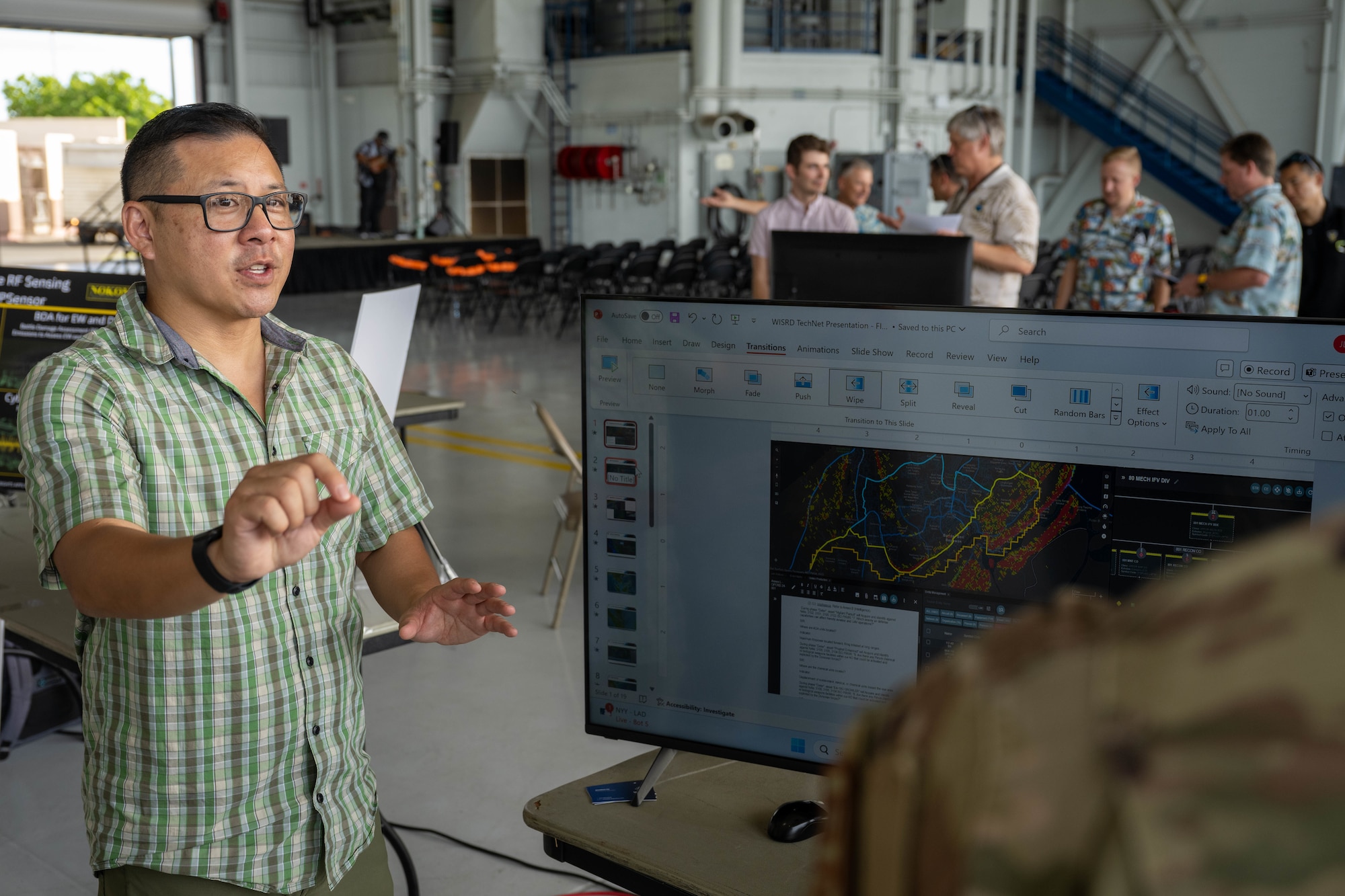 A man speaks during an expo inside an aircraft hangar.
