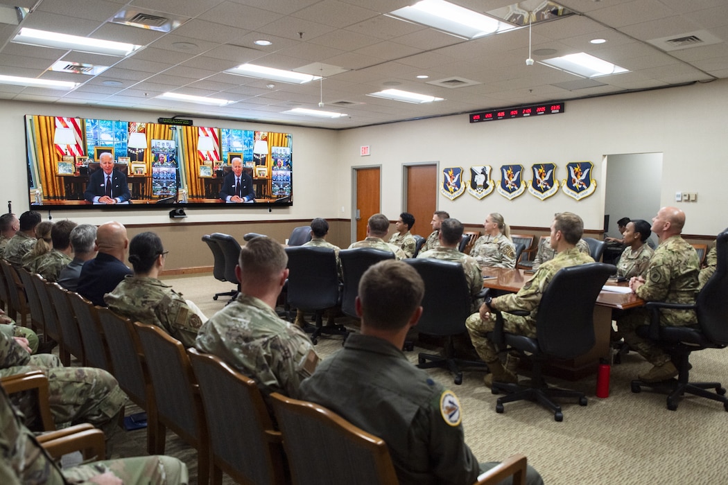 Military members watch participants of a conference call