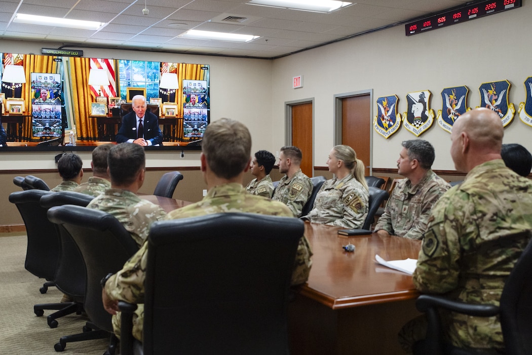 Military members sit around a conference table during a call with the U.S. president