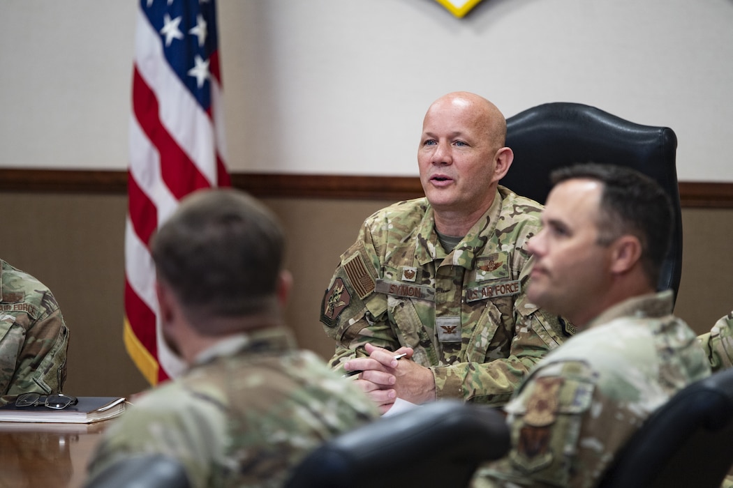 A military member sits at the front of a conference table