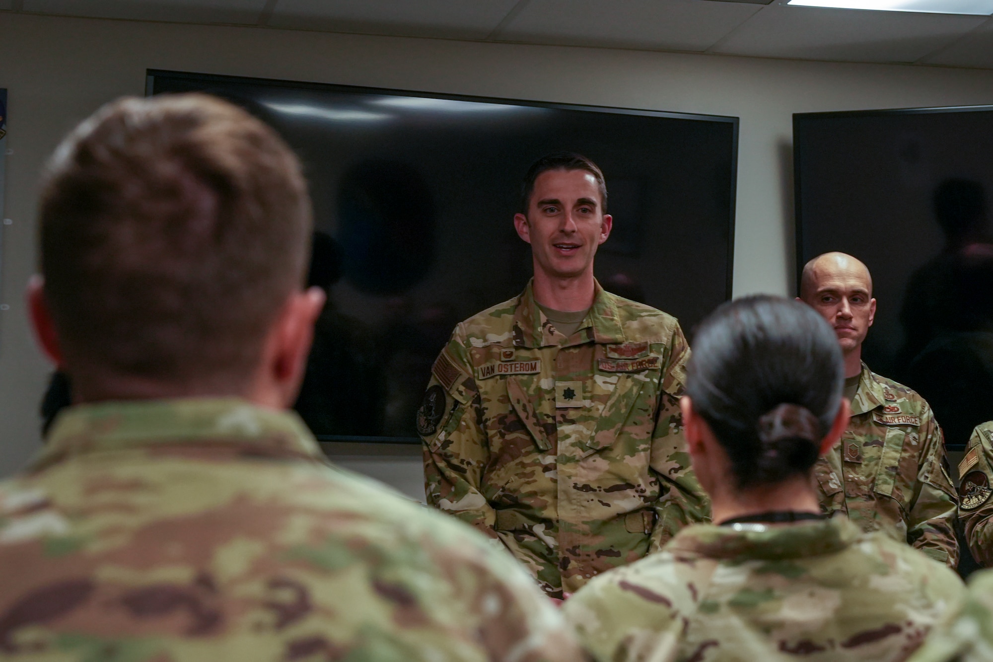 Individuals in military uniforms address a classroom of military students.