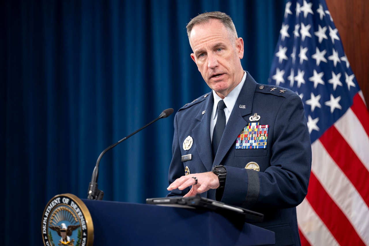 A man speaks from a podium with an American flag in the background.
