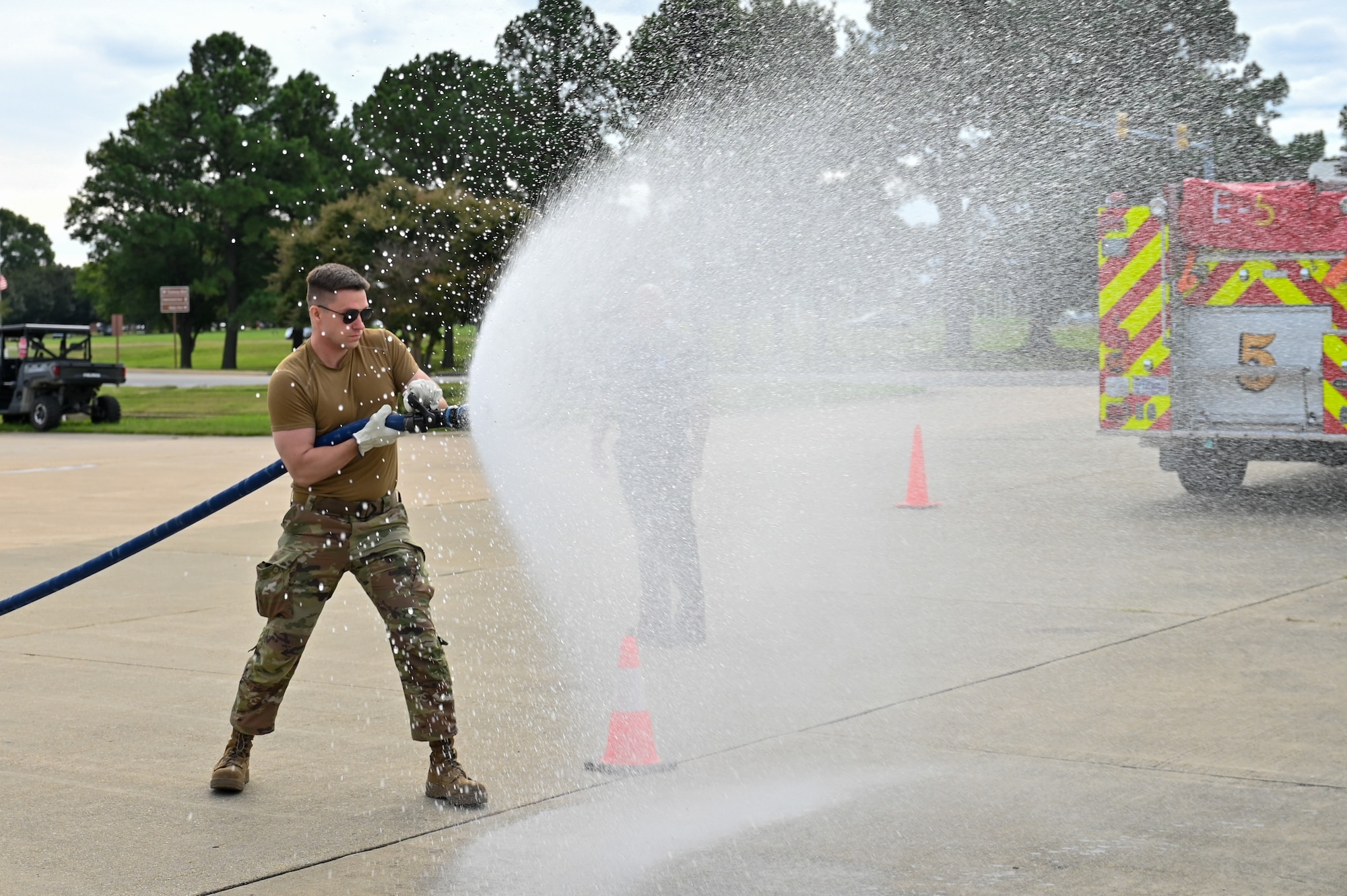 A male Airman holds a fire hose