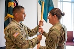 U.S. Army Col. Isaac Martinez, chief of joint staff, passes the Basic Leader Course guidon to U.S. Army Master Sgt. Sarah Miller as a sign of trust in her ability to fulfill the commandant position, Fort Carson, Colorado, Sept. 8, 2024. Miller returns to the 168th Regiment after her most recent assignment as the 117th Space Battalion operations non-commissioned officer and the 1158th Space Support Company first sergeant. (U.S. Army National Guard photo by Staff Sgt. Taylor Lakey-Tamacori)