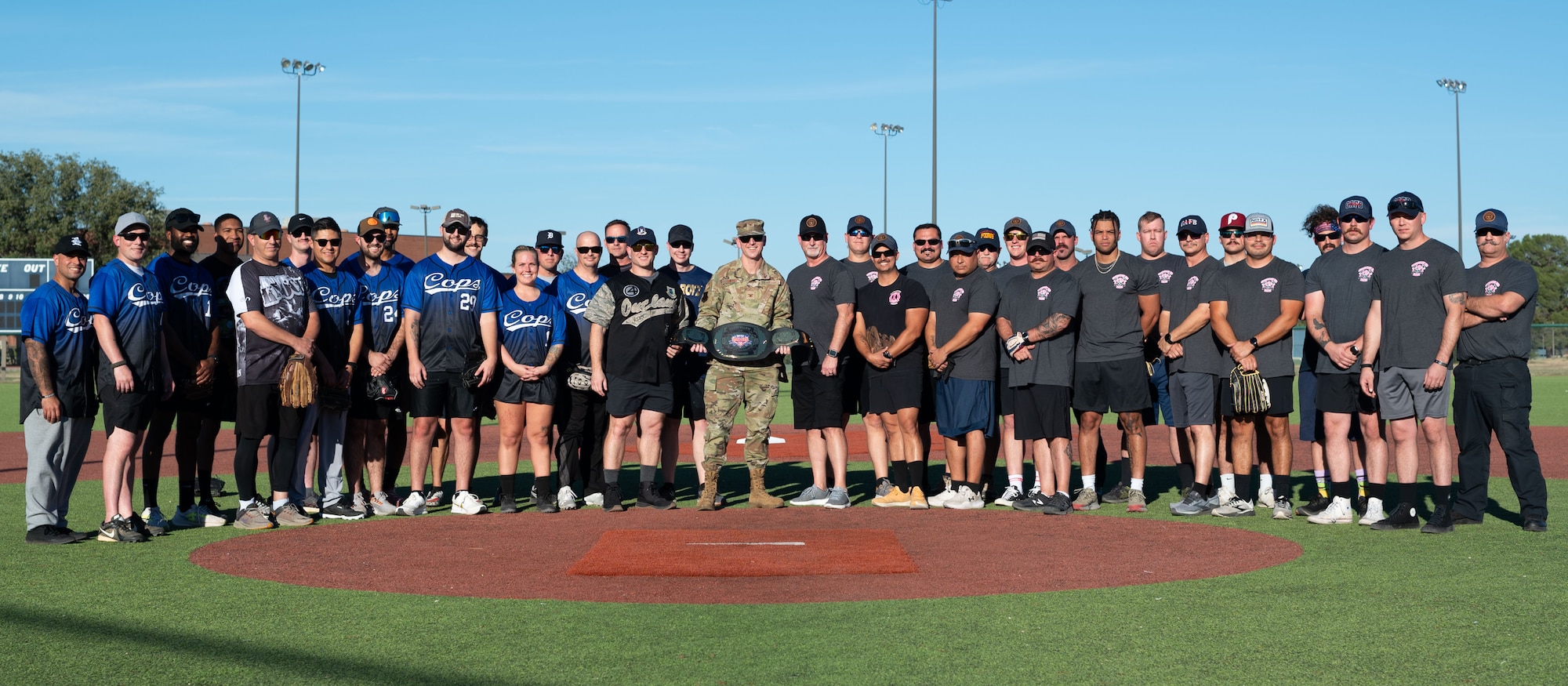U.S. Air Force Col. Thomas Wilson, 17th Training Wing deputy commander, poses for a group photo with the 17th Security Forces Squadron and 17th Civil Engineering Squadron Fire Department before the Inaugural Battle of the Badges softball game at the Mathis Fitness Center, Goodfellow Air Force Base Texas, Oct. 28, 2024. The firefighters started the game with an extra point because they had one more pint of blood donated by the end of the blood drive. (U.S. Air Force photo by Airman 1st Class Brian Lummus)