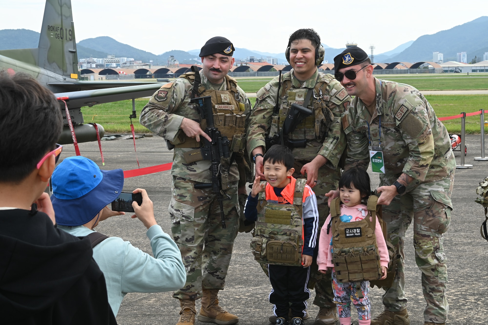 U.S. Air Force Master Sgt. Antonio Caraballo, Staff Sgt. Andres Cano, and Tech. Sgt. Shawn Harris, 51st Security Forces Squadron members, take photos with children during the Sacheon Airshow 2024 in Gyeongnam, Republic of Korea, Oct. 25, 2024. The 51st SFS provided round the clock security for Seventh Air Force aircraft participating in the ROKAF-hosted show. (U.S. Air Force photo by Master Sgt. Rachelle Coleman)