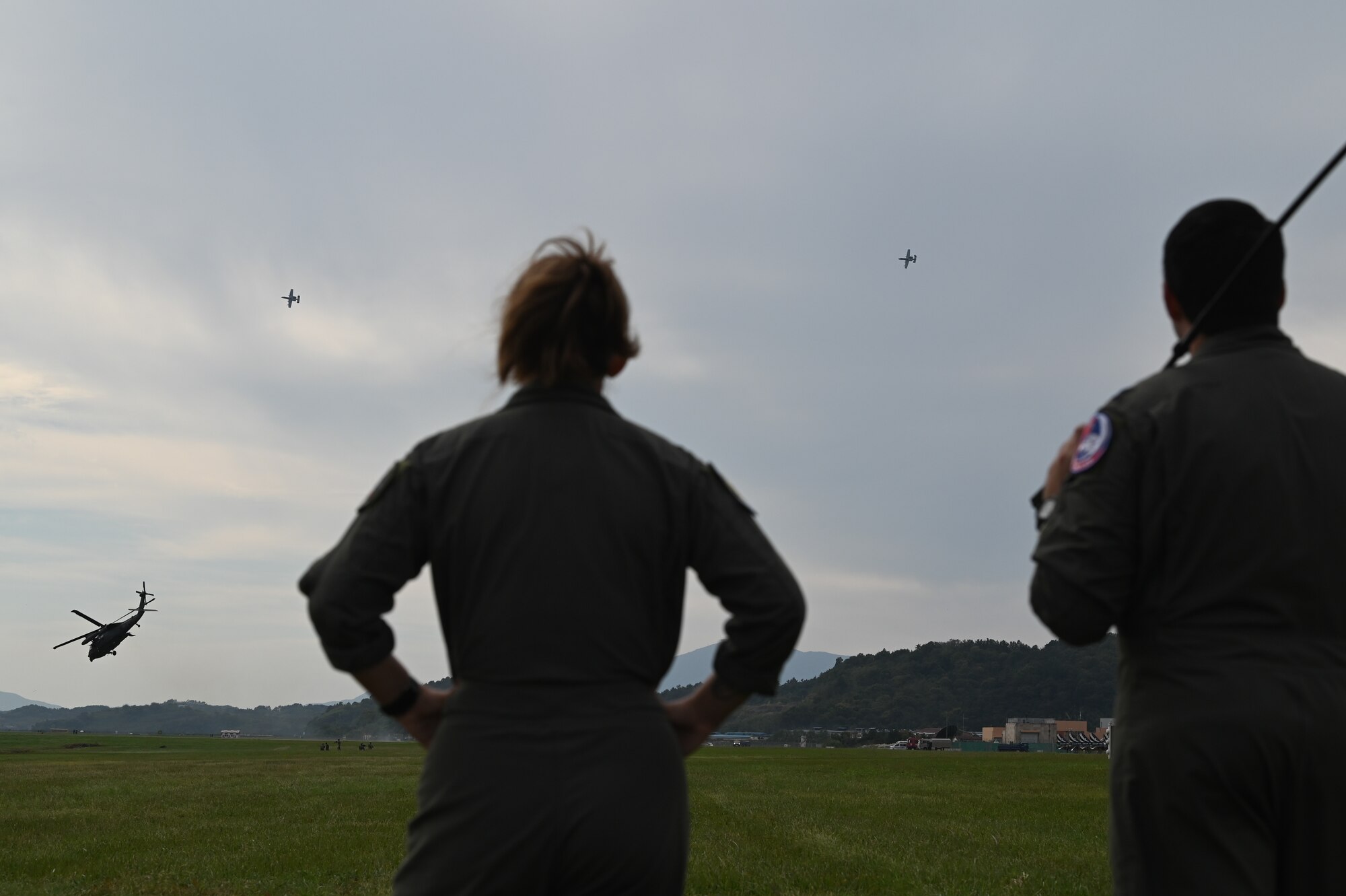 Capts. Haeley Deeney and Chris Hildago, 25th Fighter Squadron pilots, watch as two 25th FS A-10 Thunderbolt II provide air support during a combat search and rescue demonstration at the Sacheon Airshow 2024 in Gyeongnam, Republic of Korea, Oct. 25, 2024. Seventh Air Force supported the airshow with two static aircraft displays and participated in the daily CSAR demo. (U.S. Air Force photo by Master Sgt. Rachelle Coleman)