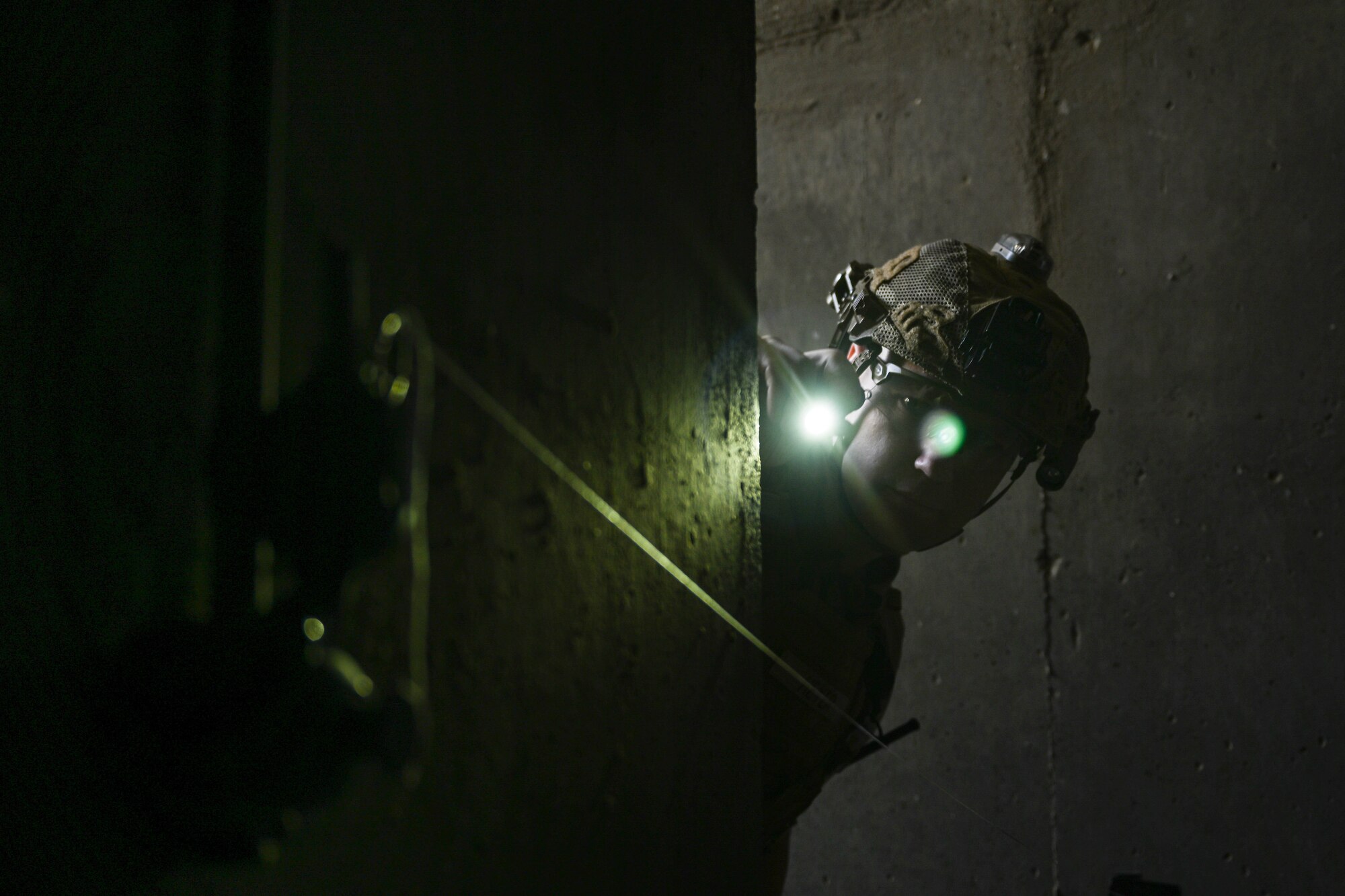 A man in uniform shines a light at a simulated grenade.