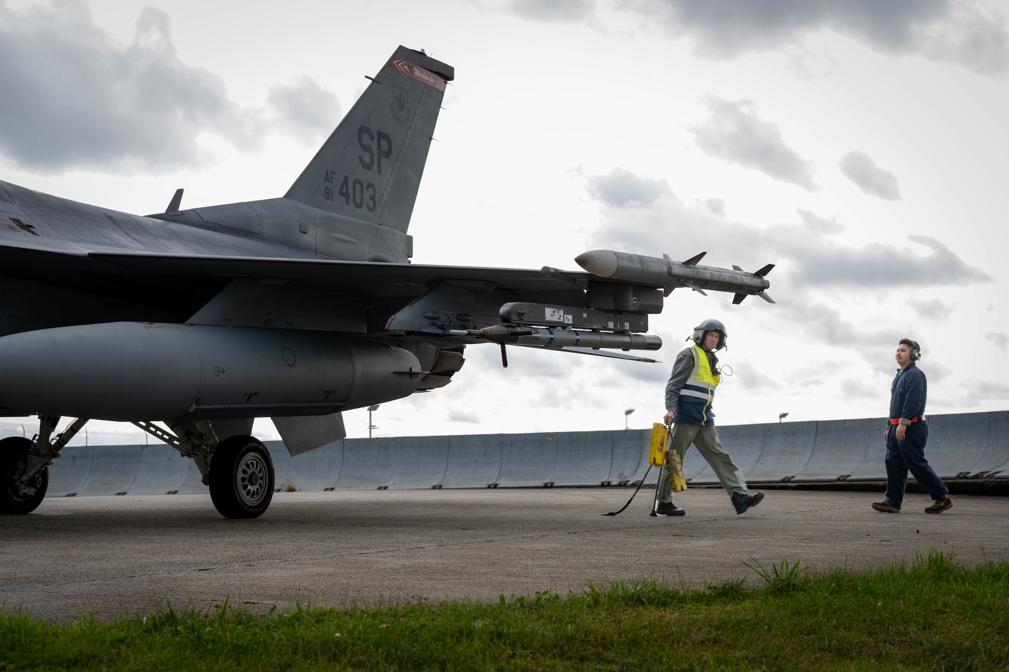 German Luftwaffe maintainer walks to place chocks under an F-16.