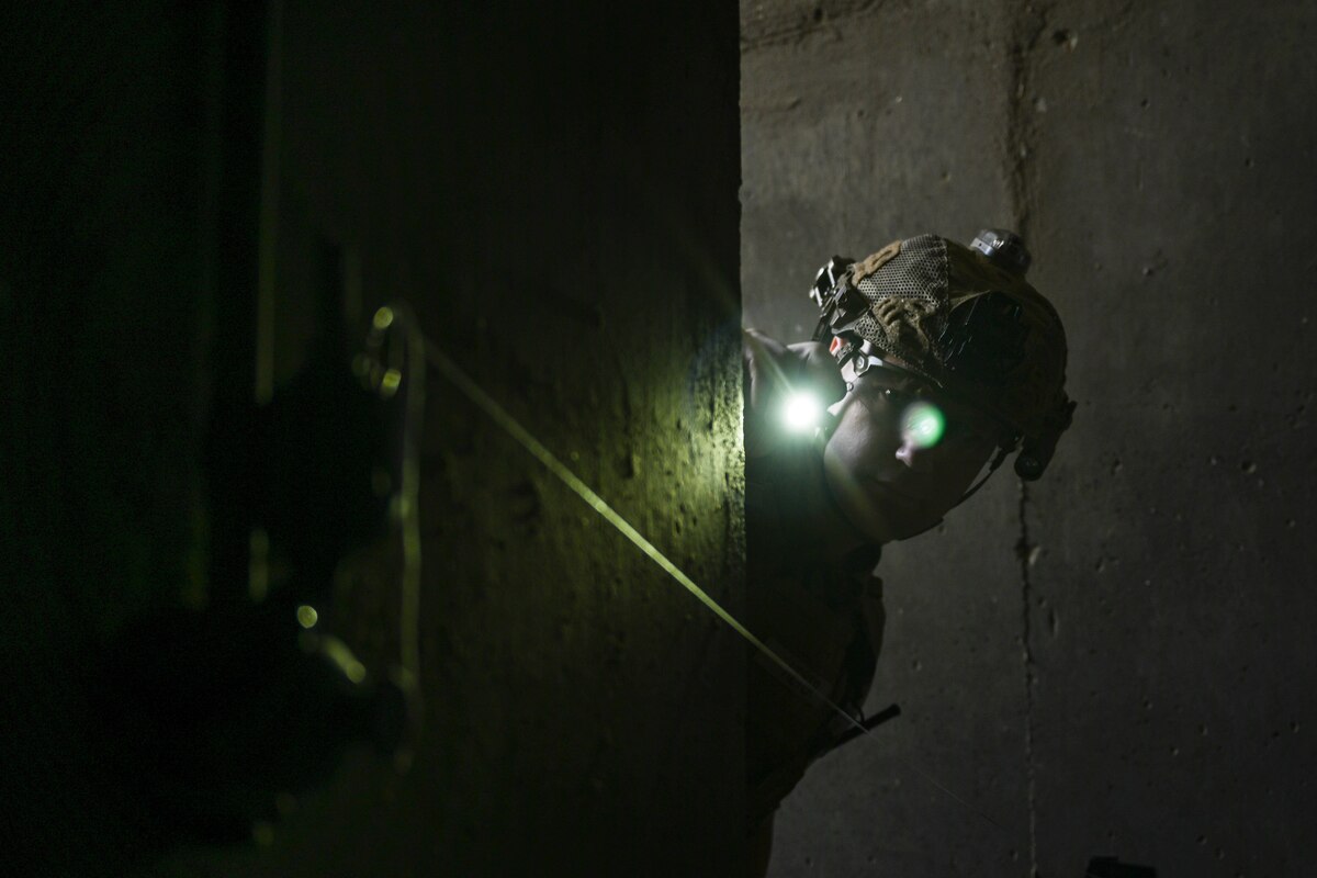 A man in uniform shines a light at a simulated grenade.