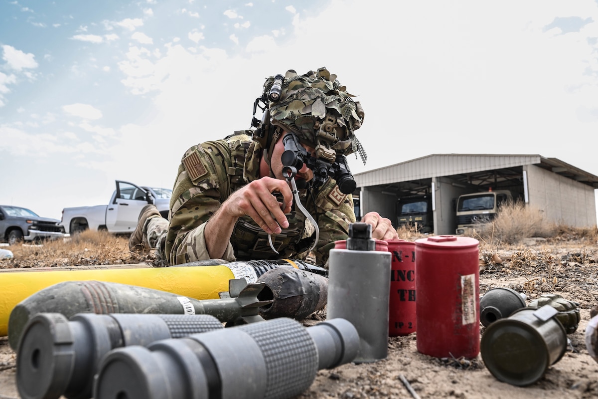 A man in uniform measures a simulated explosive device.