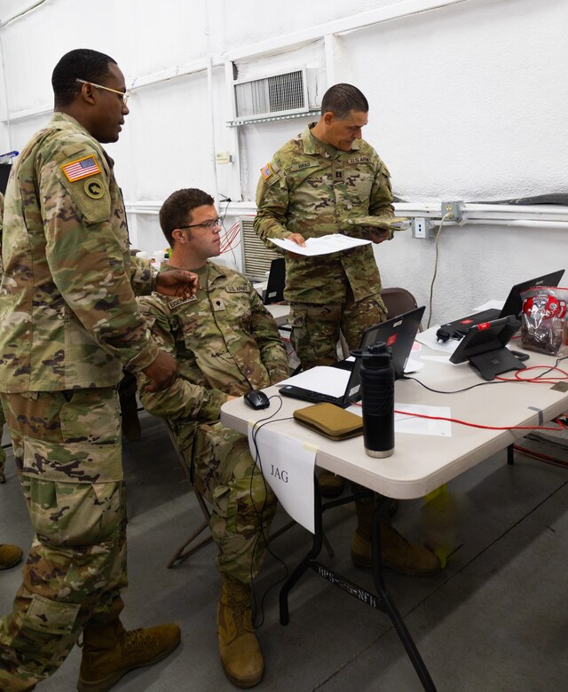 Capt. Robert McKnight, administrative law attorney, 1st Theater Sustainment Command, performs two roles during the 17th Sustainment Brigade's culminating training exercise, October 9, 2024. He was both trainer and evaluator. Here he works with Spc. Noah   Eisenbraun, paralegal specialist, 17th SB, while Capt. Richard Haas, attorney, listens, Fort Cavazos, Texas.