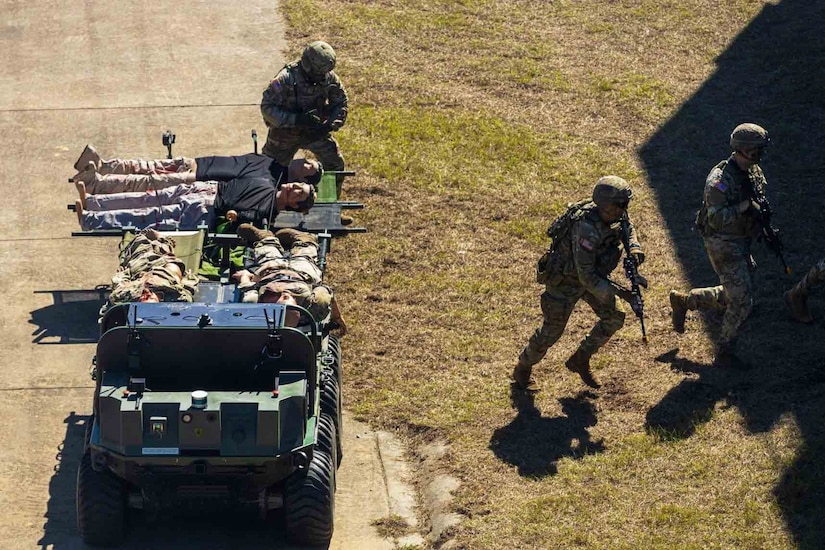 Soldiers run from a military vehicle carrying simulated casualties.