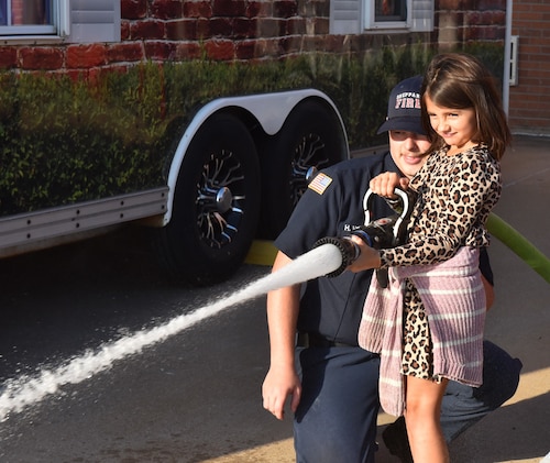 firefighter helps student use fire hose