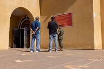 A U.S. Marine Corps drill instructor with 3rd Recruit Training Battalion, Recruit Training Regiment, Marine Corps Recruit Depot San Diego, tours the yellow footprints with Terry and Dustin Bringham, the son and grandson of the late Capt. Gary L. Bringham, at MCRD San Diego, California, Oct. 21, 2024. From 1962 to 1965, Gary Bringham served as a drill instructor at MCRD San Diego before commissioning and retiring as a captain. The Bringham family toured the depot to learn more about his role as a drill instructor and the significance of training recruits. (U.S. Marine Corps photo by Cpl. Alexander O. Devereux)