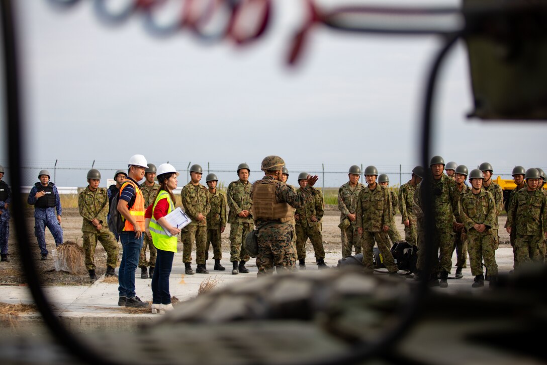 U.S. Marine Corps Cpl. Jose Estrada, a combat engineer with Marine Wing Support Squadron 171, Marine Aircraft Group 12, 1st Marine Air Wing, and a native of Florida, talks  to Japan Ground Self-Defense Force members with 13th Brigade, Middle Army, and Japan Maritime Self-Defense Force members with Fleet Air Wing 31, about airfield damage repair capabilities during exercise Keen Sword 25 at Marine Corps Air Station Iwakuni, Oct. 25, 2024. Keen Sword is a biennial, joint and bilateral field-training exercise involving U.S. military and Japan Self-Defense Force personnel, designed to increase readiness and interoperability while strengthening the ironclad U.S.-Japan alliance. (U.S. Marine Corps photo by Cpl. Peter Rawlins)