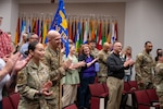 Uniformed members and civilians clap and laugh in an auditorium during an award ceremony.