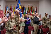 Uniformed members and civilians clap and laugh in an auditorium during an award ceremony.