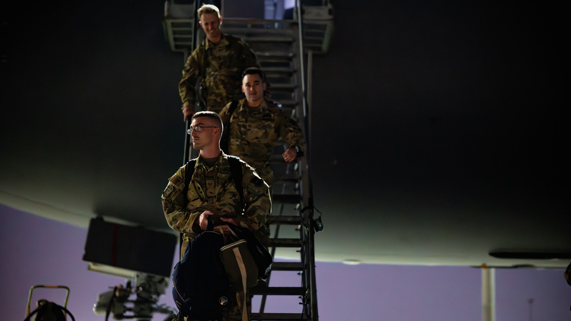 Three Airmen exit an aircraft.