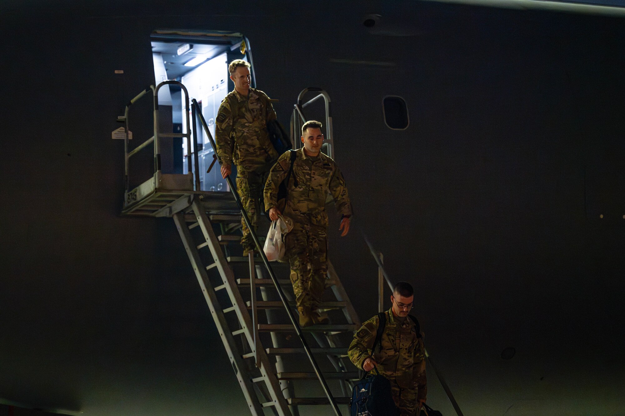 Three Airmen depart aircraft.