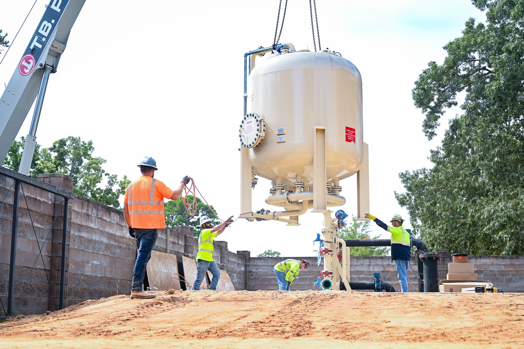 Contractors help a crane lower equipment into a water treatment facility.