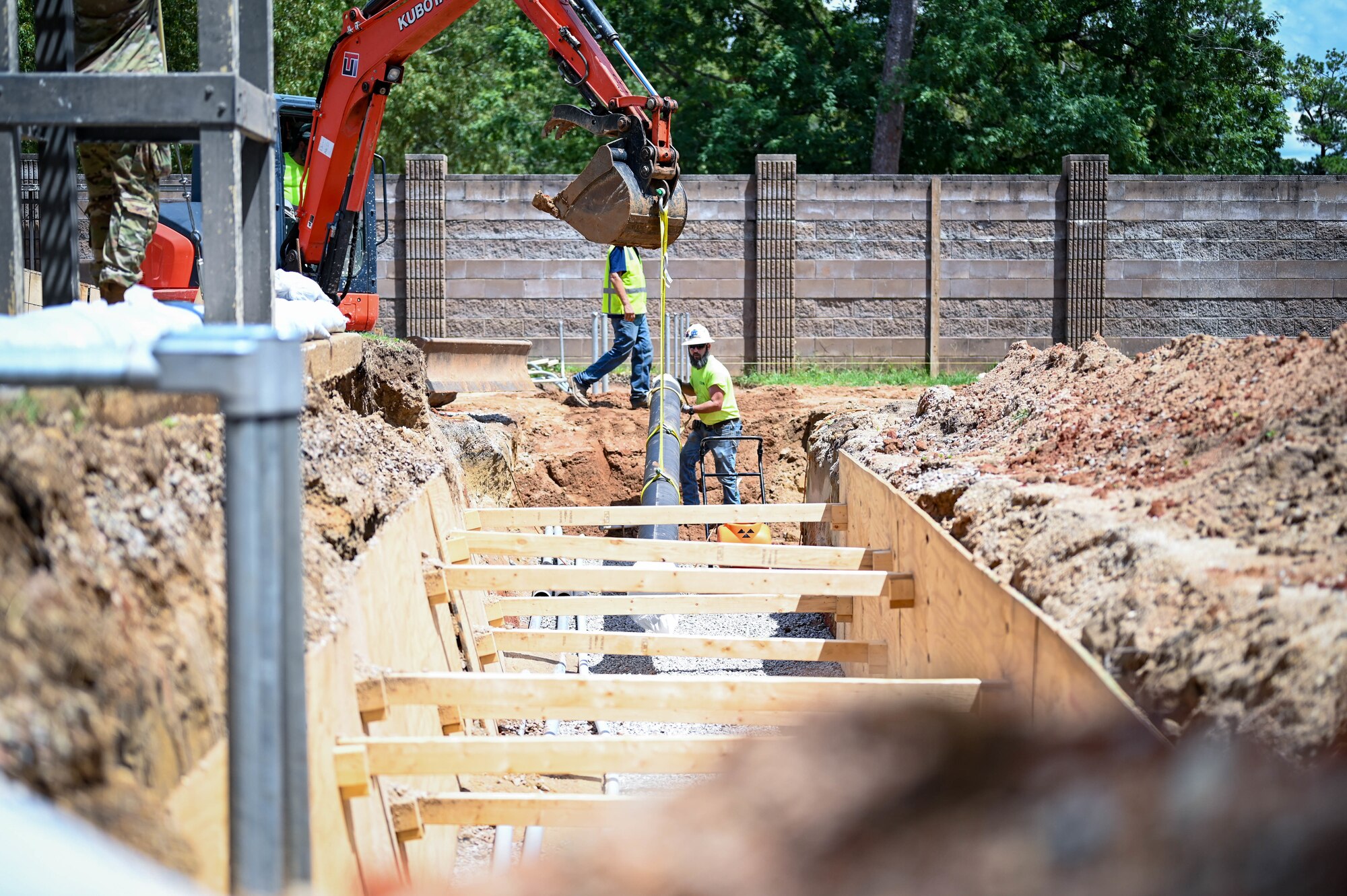 A contractor helps navigate pipes down with a crane.