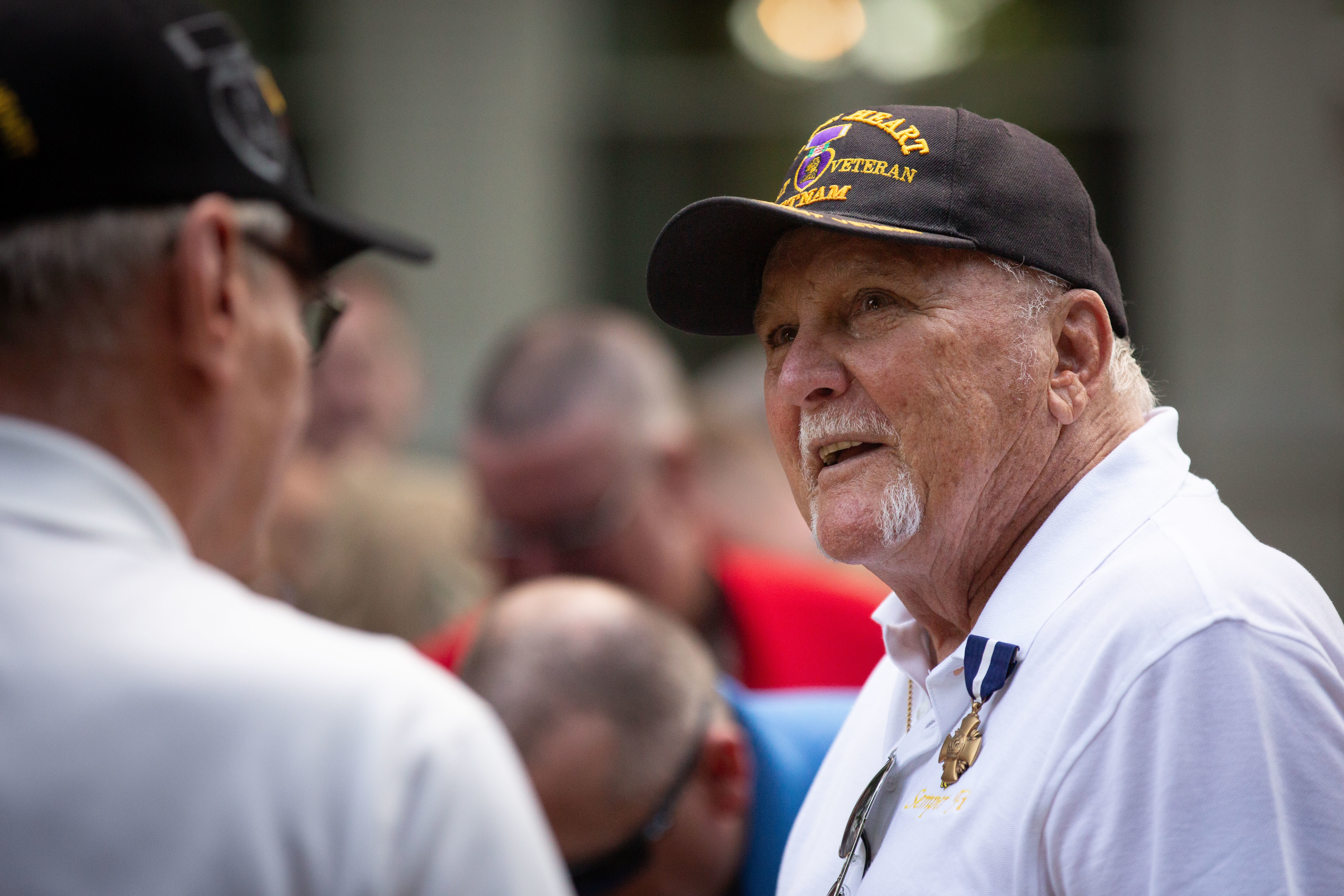 A Vietnam veteran in a cap speaking to another man.