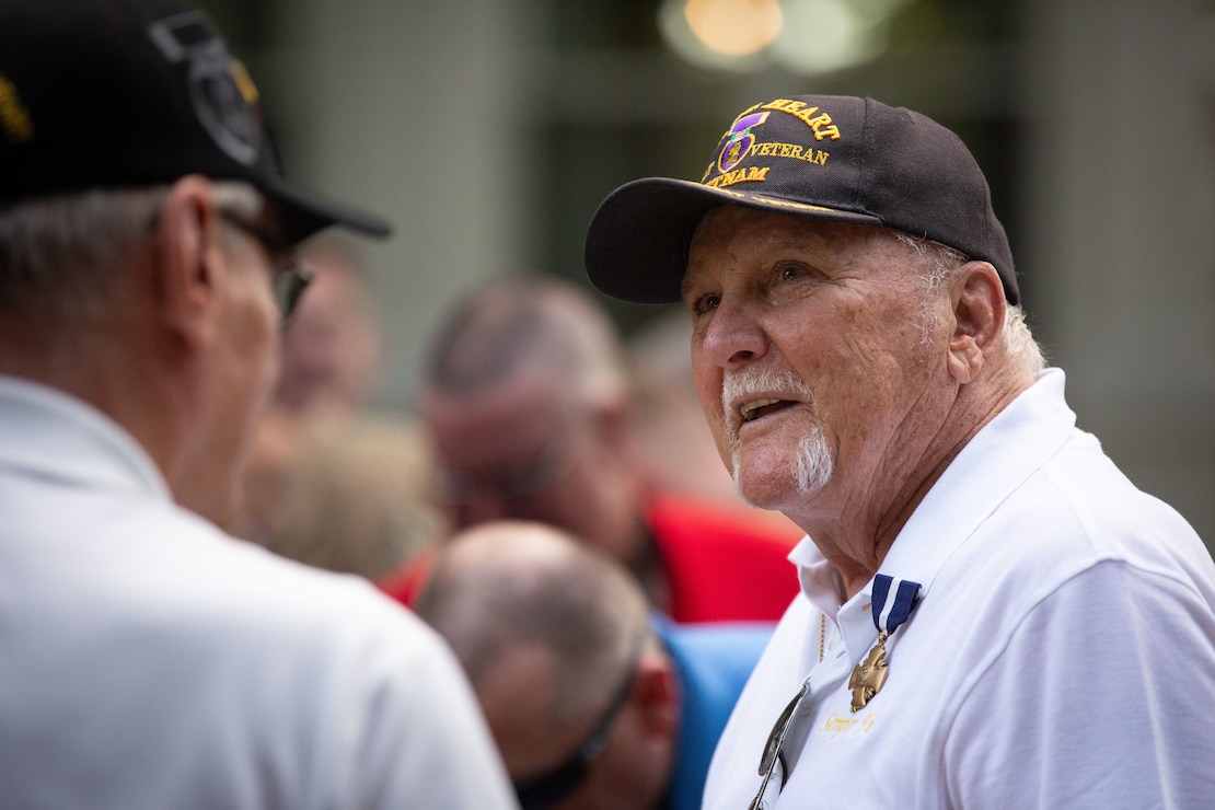 A Vietnam veteran in a cap speaking to another man.