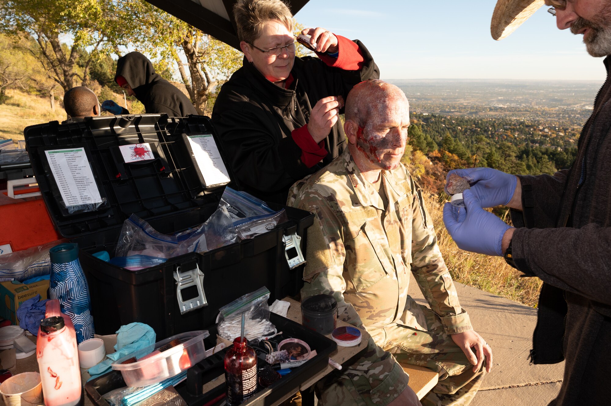 A zombie performer sits as volunteers apply moulage prior to the start of the zombie run.