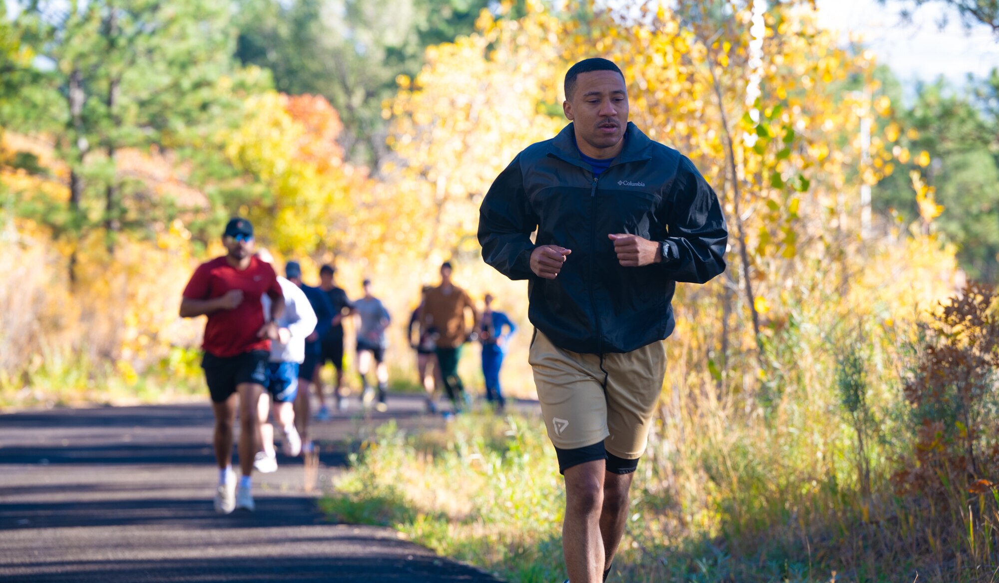 A participant ahead of other runners, is running uphill on the event trail.