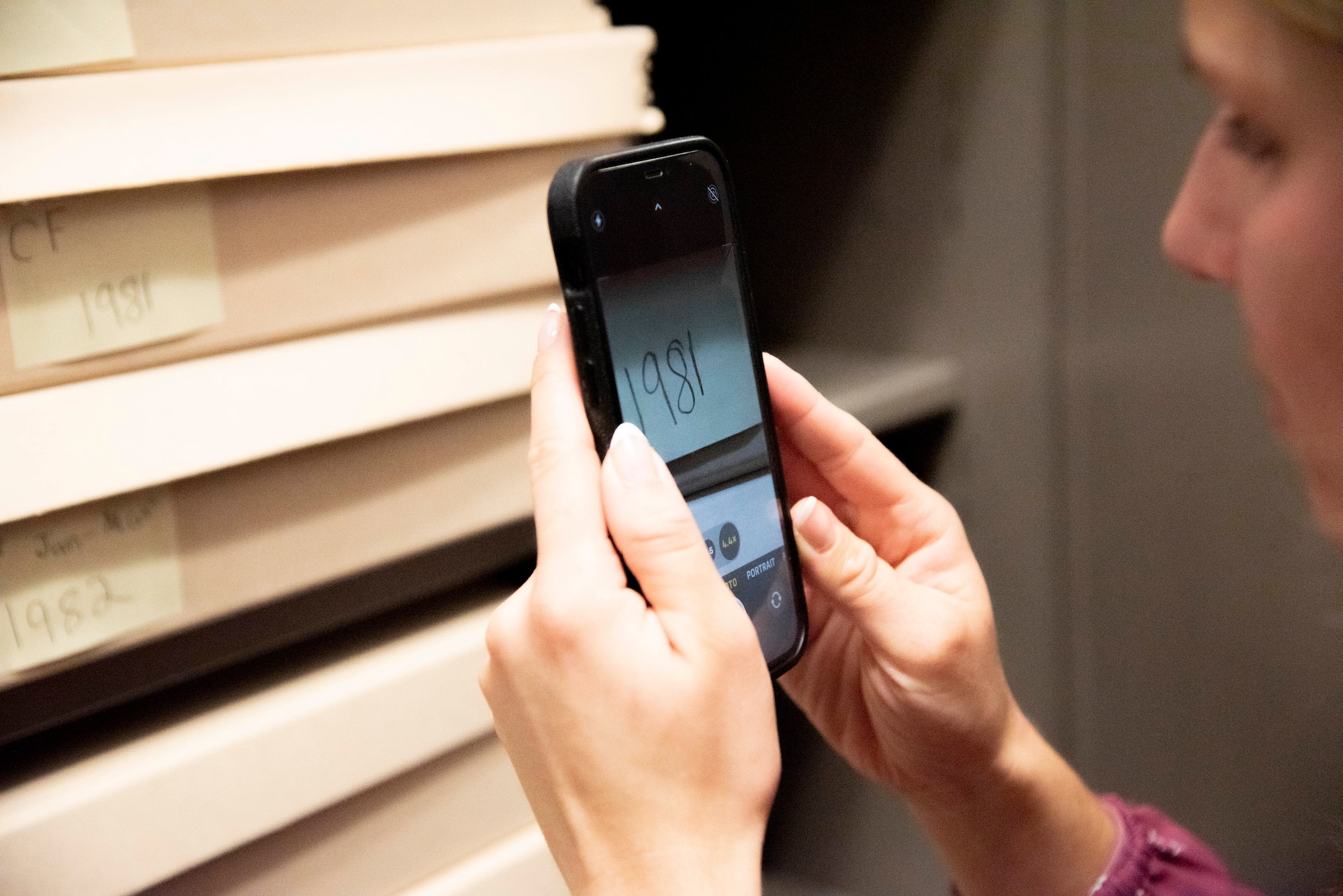 Meaghan M. Kacmarcik, 316th Wing deputy historian, uses her phone to magnify labels on archival material at Joint Base Andrews, Md., Oct. 24, 2024. Due to vision loss caused by Stargardt disease, Kacmarcik uses technology to aid in her work. (U.S. Air Force photo by Patrick Griffith)