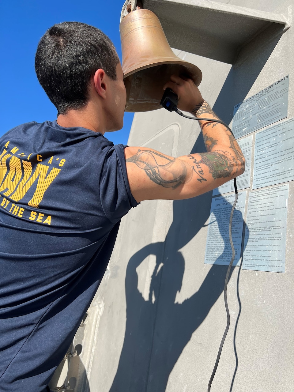 A sailor writes in the inside of a small bell.