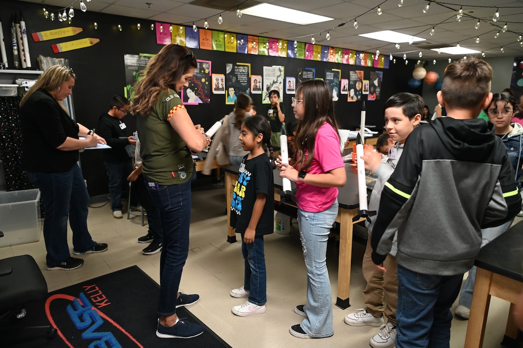 Retired Air Force Lt. Cols. Caroline “Blaze” Jensen (left) and Olga Custodio (center) sign rockets that elementary school students will get to fire as part of Starbase Kelly, which is a Department of Defense program designed to introduce underprivileged students to science, technology, engineering, and math, at Joint Base San Antonio-Lackland, Texas Oct. 10, 2024.