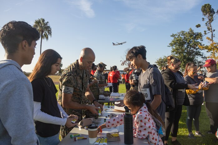 U.S. Marine Corps 1st Sgt. Anthony Castillo, first sergeant with Service Company, Headquarters and Service Battalion, Marine Corps Recruit Depot San Diego hands out face paint prior to the 2024 Marine Corps Recruit Depot San Diego Boot Camp Challenge at MCRD San Diego, California, Oct. 19, 2024. For the past 23 years, MCRD San Diego has hosted the bootcamp Challenge, a three-mile obstacle course race guided by 60 drill instructors that highlights the physical and mental demands of bootcamp. The event fosters camaraderie and community engagement through interaction with MCRD personnel. (U.S. Marine Corps photo by Lance Cpl. Janell B. Alvarez)