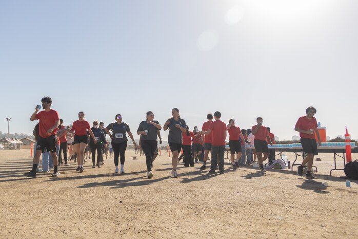 Contestants of the 2024 Marine Corps Recruit Depot San Diego Boot Camp Challenge receive cups of water during the Boot Camp Challenge at MCRD San Diego, California, Oct. 19, 2024. For the past 23 years, MCRD San Diego has hosted the bootcamp Challenge, a three-mile obstacle course race guided by 60 drill instructors that highlights the physical and mental demands of bootcamp. The event fosters camaraderie and community engagement through interaction with MCRD personnel. (U.S. Marine Corps photo by Lance Cpl. Janell B. Alvarez)