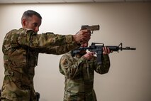 U.S. Air Force Brig. Gen. Stephen Snelson, U.S. Air Force Expeditionary Center commander, and Chief Master Sgt. Dennis Fuselier, USAFEC command chief, participate in a firearms simulator demonstration during a visit to Joint Base Charleston, South Carolina, Oct. 30, 2024. The USAFEC command team engaged with Airmen and Sailors across the installation, observing firsthand their innovative approaches to enhancing mission success and operational readiness.