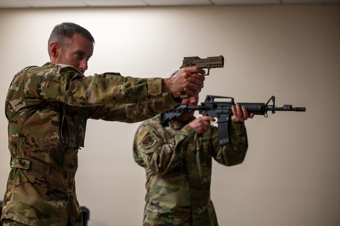U.S. Air Force Brig. Gen. Stephen Snelson, U.S. Air Force Expeditionary Center commander, and Chief Master Sgt. Dennis Fuselier, USAFEC command chief, participate in a firearms simulator demonstration during a visit to Joint Base Charleston, South Carolina, Oct. 30, 2024. The USAFEC command team engaged with Airmen and Sailors across the installation, observing firsthand their innovative approaches to enhancing mission success and operational readiness.