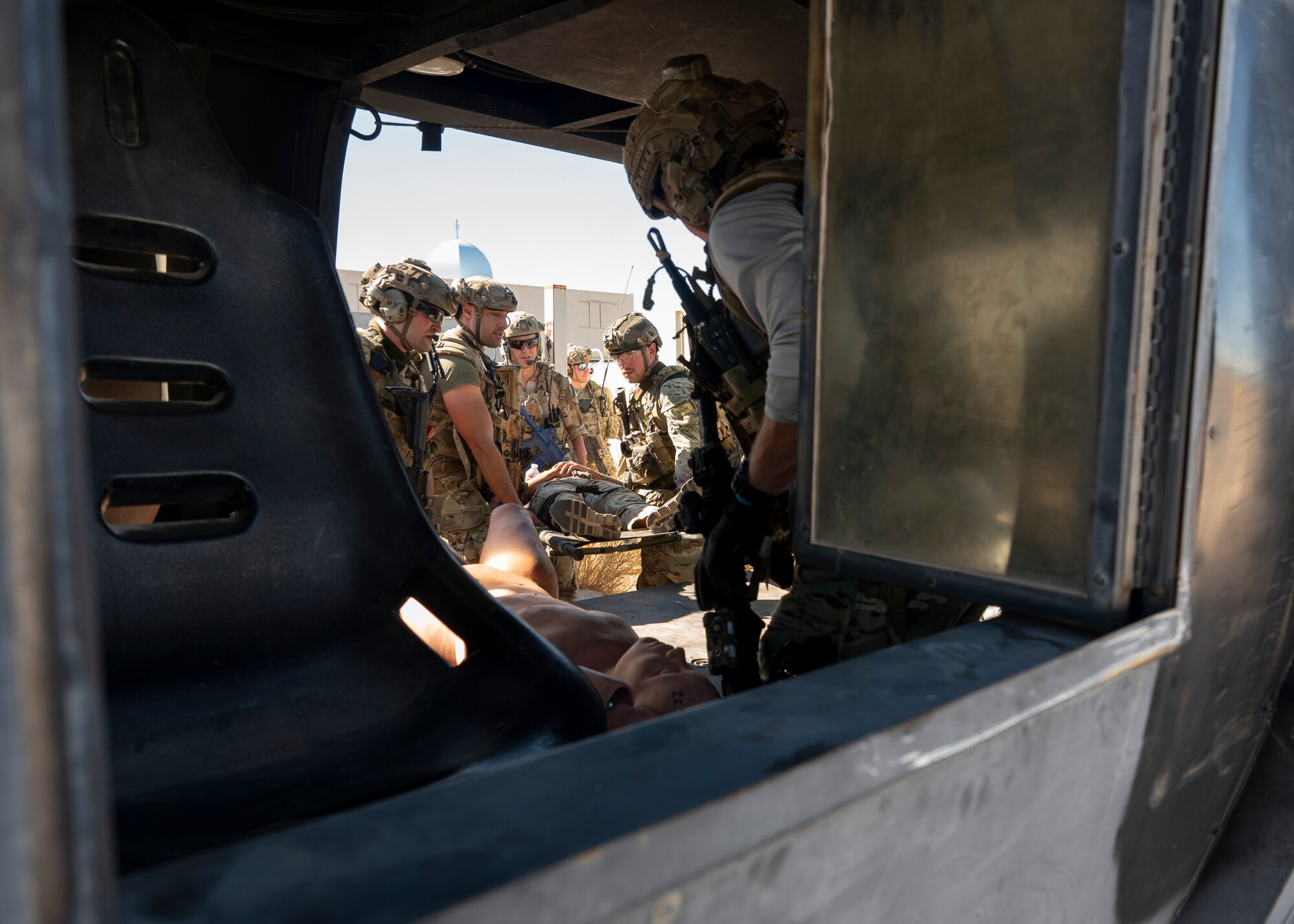 A group of men in military clothing carry a simulated casualty onto an aircraft.