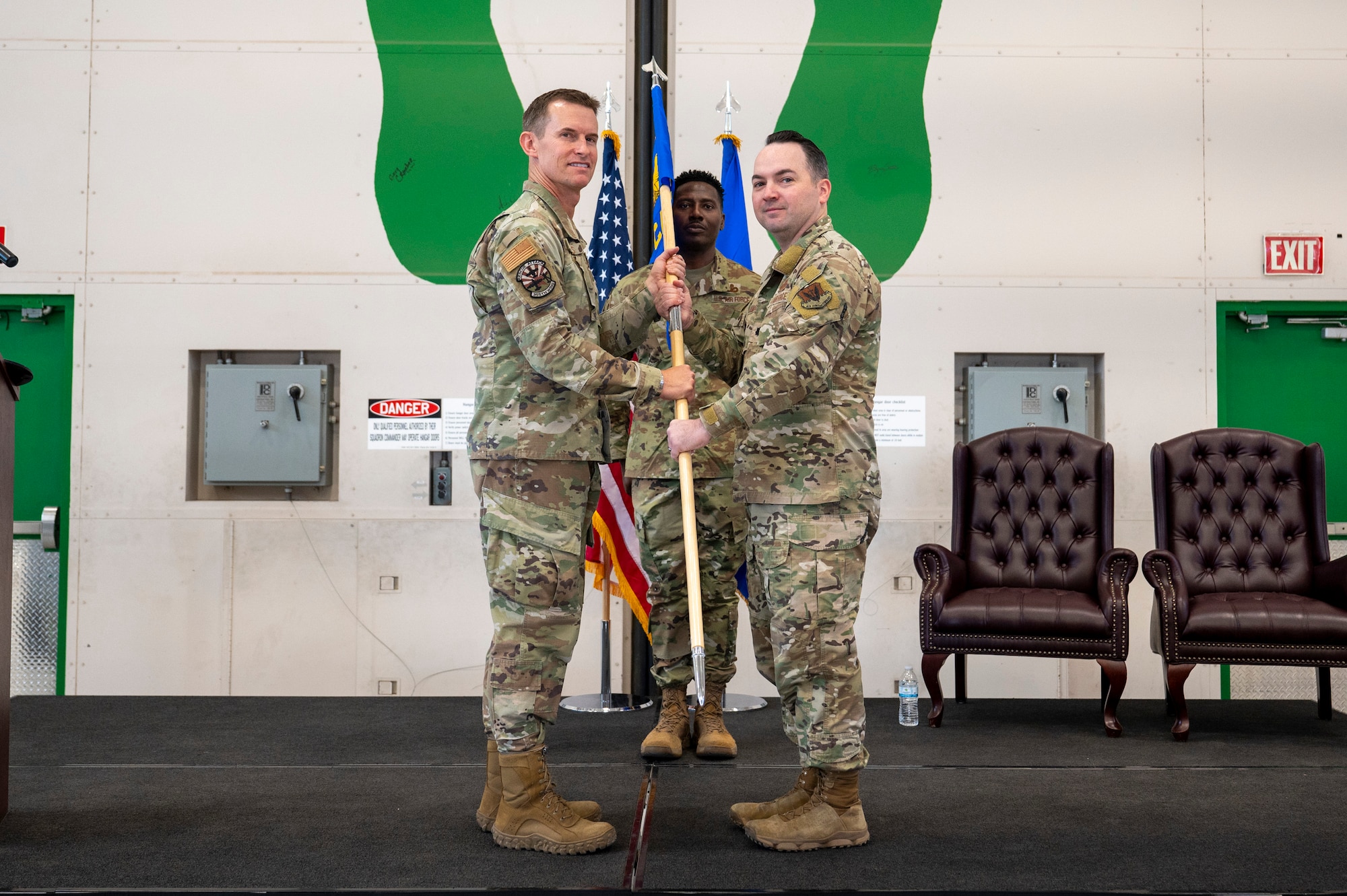 U.S. Air Force Col. Scott Mills, 355th Wing commander, left, presents the guidon to Lt. Col. Daniel Jamerson, 11th Combat Air Base Squadron commander, right, at the activation and assumption of command for the 11th CABS at Davis-Monthan Air Force Base, Arizona, Oct. 31, 2024. Passing the guidon from Mills to Jamerson signifies Mills’ trust and squadron responsibility transferred to Jamerson. (U.S. Air Force photo by Senior Airman Devlin Bishop)
