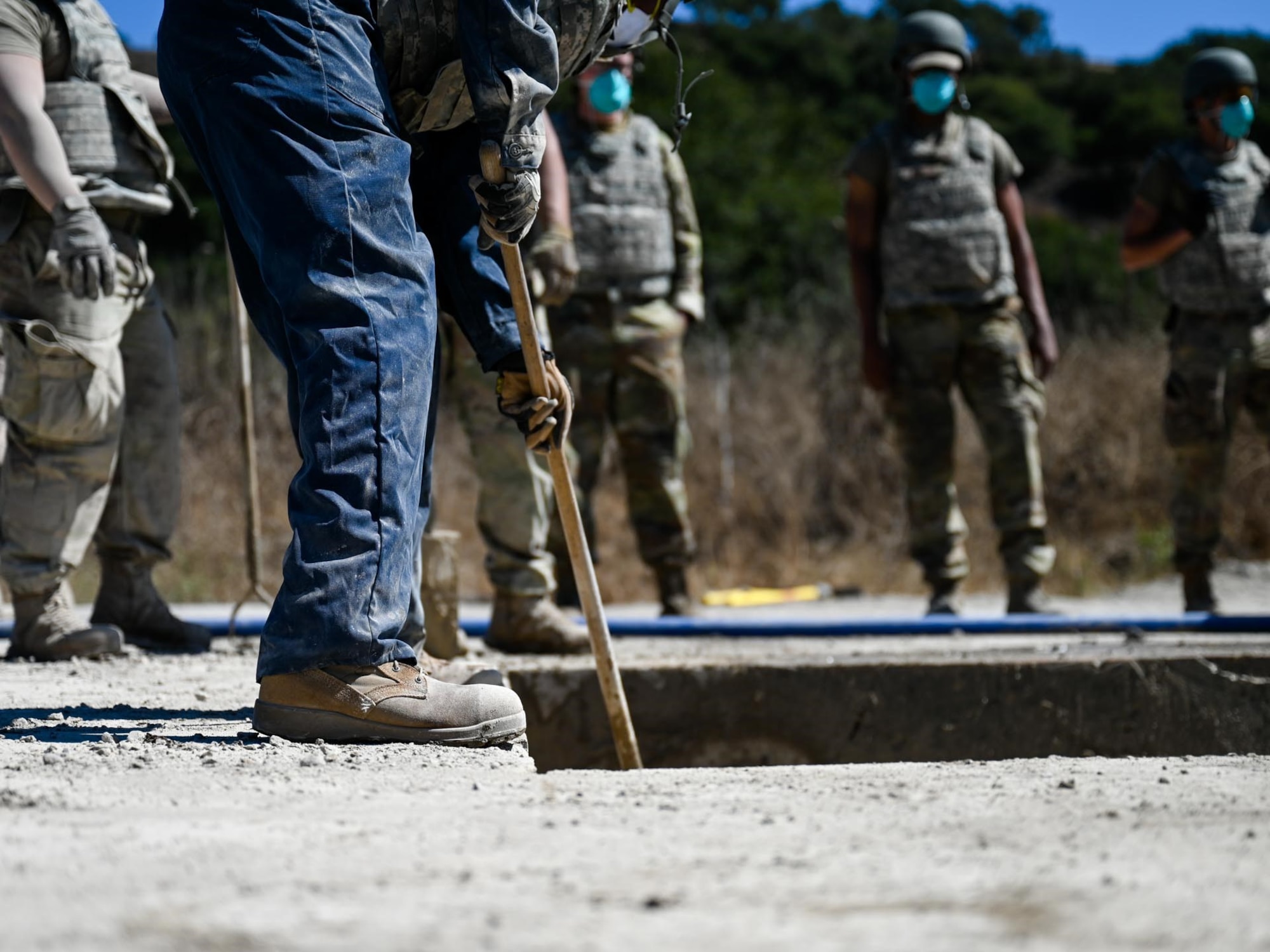 An airman mixes concrete.