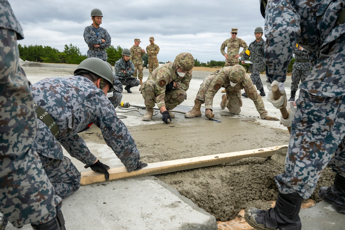 U S Air Force Airman and Japan Air Self Defense Force members smooth out concrete