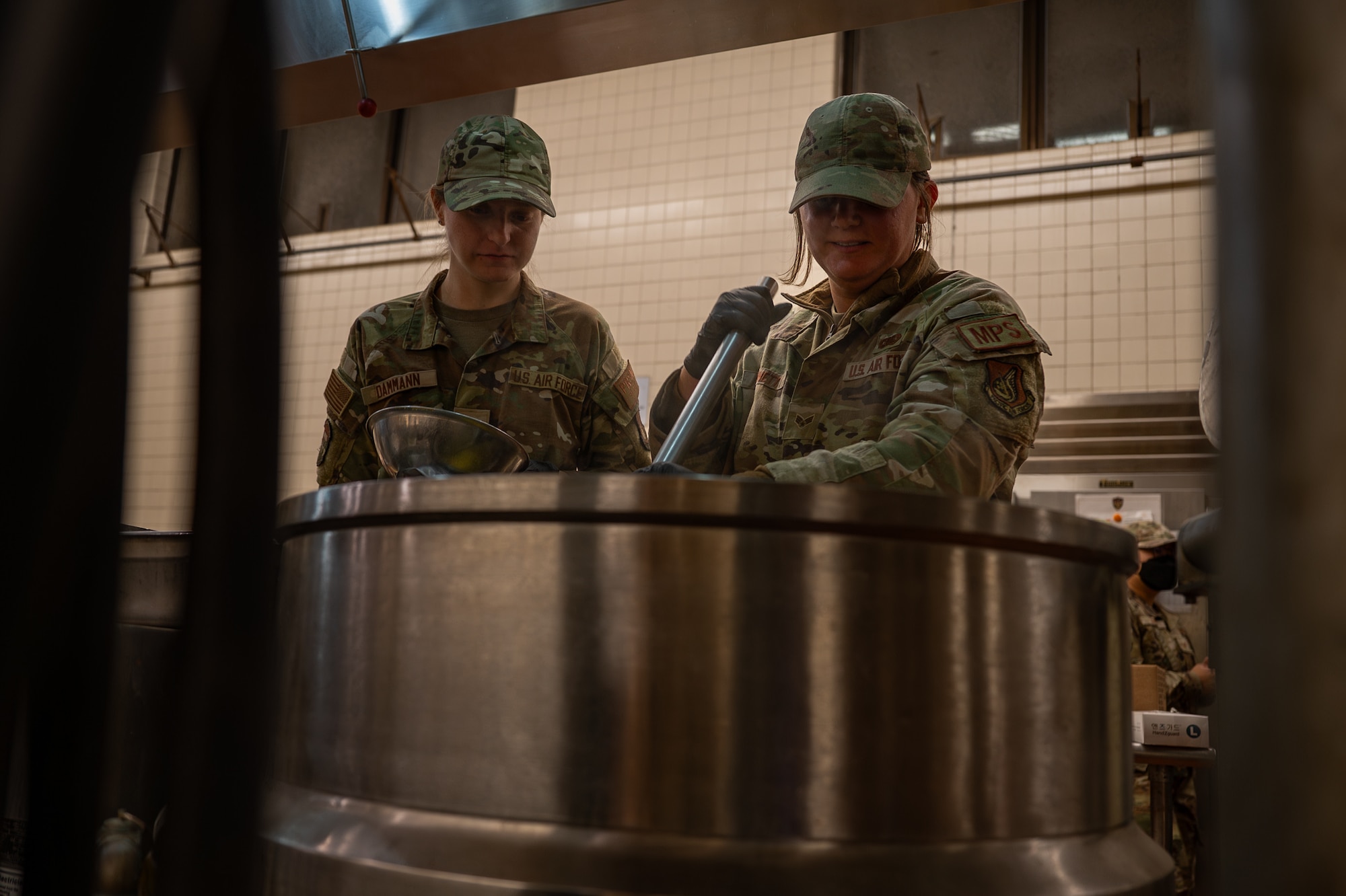 U.S. Air Force Senior Airman Taylor Bennett, right, 51st Force Support Squadron military postal clerk, and Senior Airman Mackenzie Damian, 51st FSS force management technician, cook scrambled eggs during Beverly Herd 25-1 at Osan Air Base, Republic of Korea, Nov. 1, 2024. The setup and management of the alternate dining facility during the routine training event supports mission readiness by reinforcing essential food service skills under simulated contingency conditions. (U.S. Air Force photo by Senior Airman Brittany Russell)