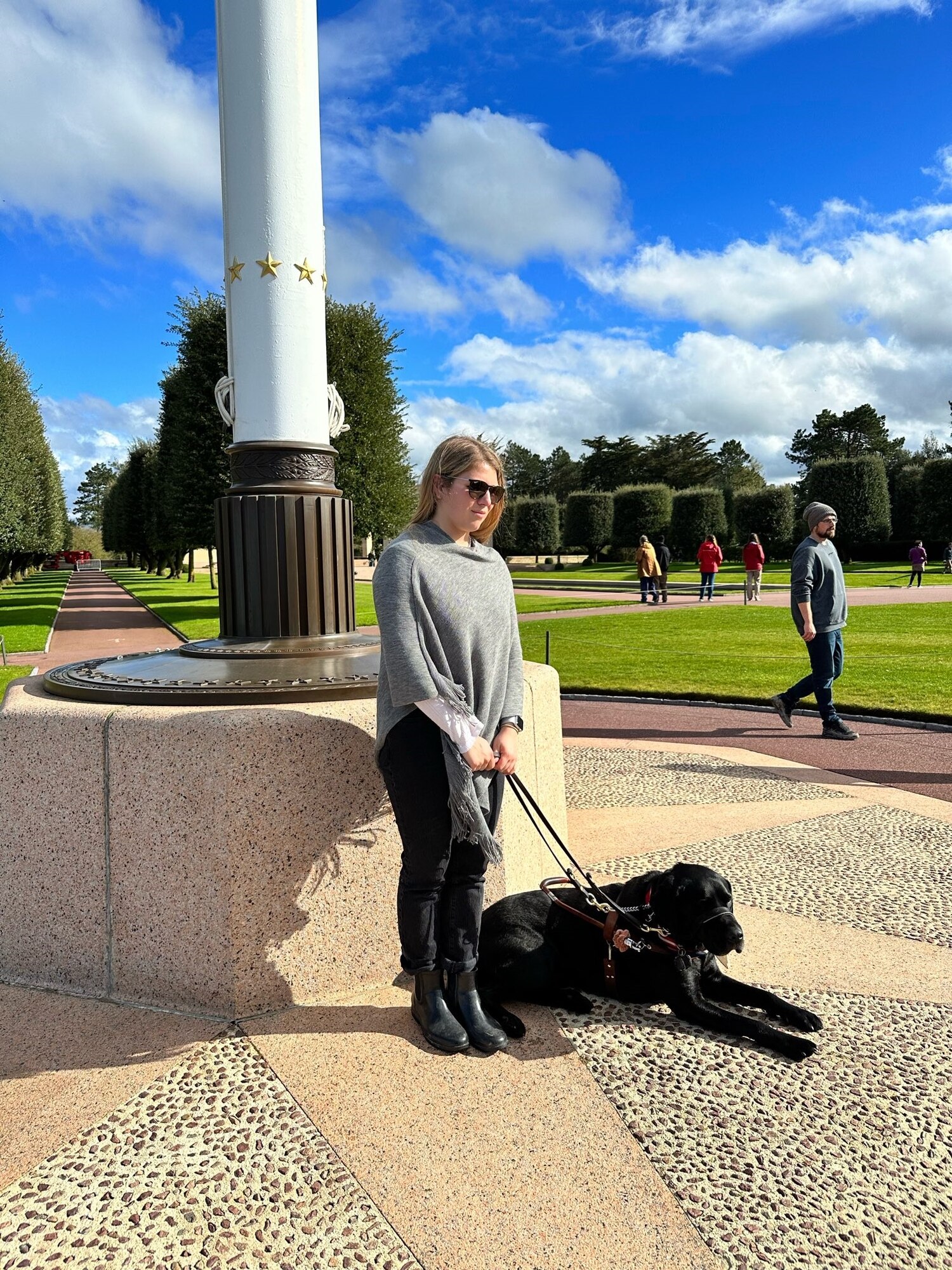 Meaghan M. Kacmarcik, 316th Wing deputy historian, and her service dog, Charlie, visit the Normandy American Cemetery and Memorial on March 18, 2023, in France. Kacmarcik wrote a biography on Army Pfc. Stanley M. Miesowicz, who is buried at the cemetery, as part of a college course project that helped her get through a tough situation in her life. (Courtesy photo)